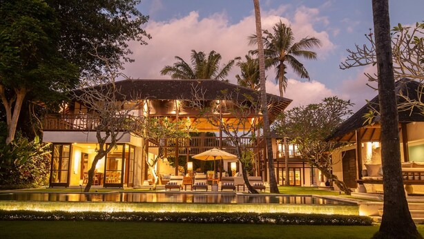 Ein großes, mehrstöckiges Resort mit Pool, Sitzgelegenheiten im Freien und Palmen.