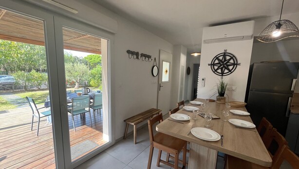 A modern kitchen with a large dining table set for four, a refrigerator, and a view of the outdoor patio. - V0755-Villa sleeps 6 in residence with communal pool close to the sea (Vias)