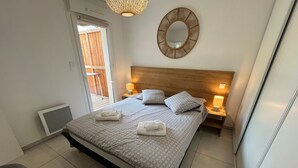 A neatly made bed with patterned bedding, a round mirror on the wall, and two bedside lamps. - V0755-Villa sleeps 6 in residence with communal pool close to the sea (Vias)