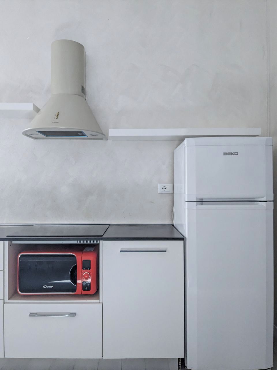 Eine Küchenzeile mit Mikrowelle, Backofen und Kühlschrank.