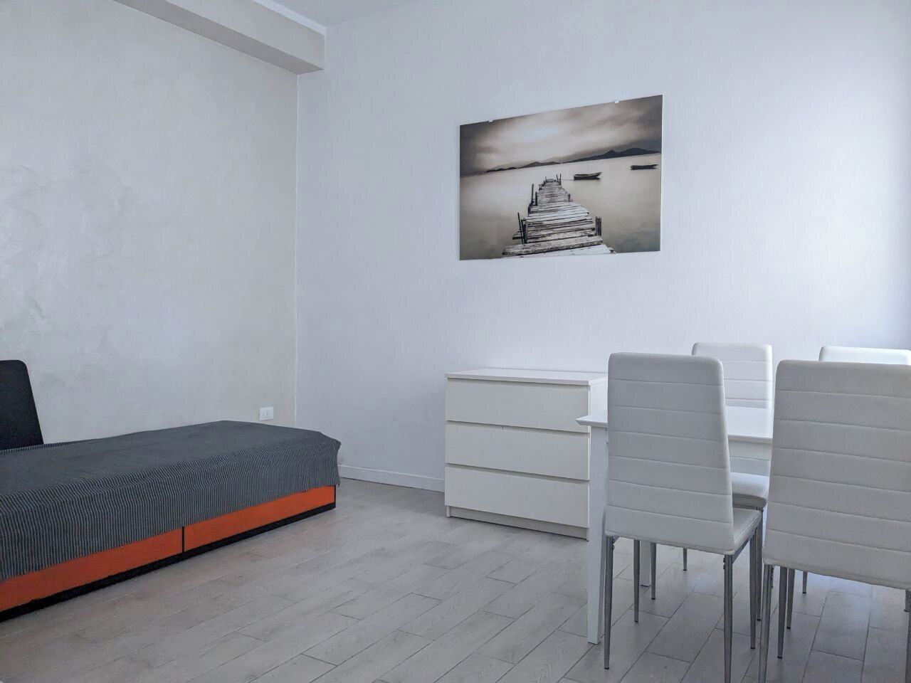 A minimalist bedroom with a bed, a desk, and a chair.