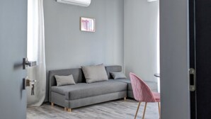 Un salon moderne avec un canapé gris, un fauteuil rose et un ventilateur de plafond.