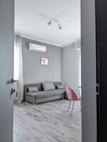 Un soggiorno moderno con un divano grigio, una poltrona rosa e una ventola a soffitto.