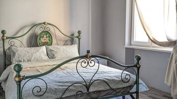 Ein Einzelbett mit grünem Metallgestell, einer gemusterten Bettdecke und einem kleinen dekorativen Gegenstand an der Kopfteil.