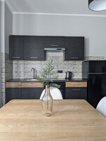 Una cucina moderna con mobili in legno scuro, una schiena a mosaico e un tavolo da pranzo in legno con un vaso.