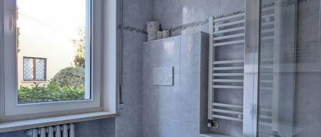 A modern bathroom with a large window, a bathtub, a toilet, and a bidet.