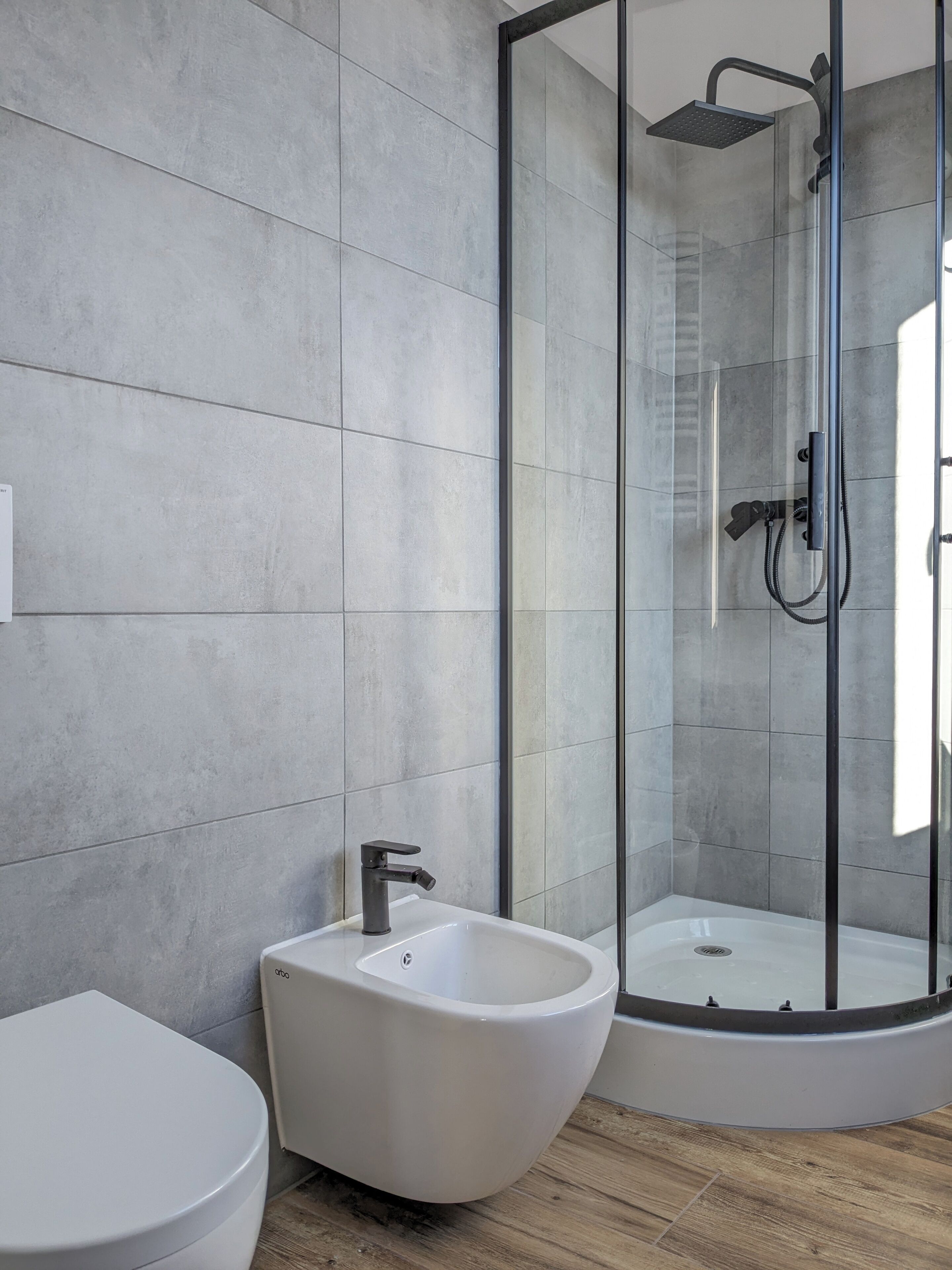 Un baño moderno con un lavamanos independiente, ducha con mampara de vidrio y un inodoro.