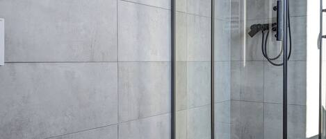 Un baño moderno con un lavamanos independiente, ducha con mampara de vidrio y un inodoro.