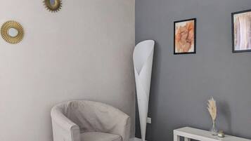 Una habitación moderna con una pared de acento gris, una lámpara de pie blanca, una mesita consola blanca con un florero y un sillón color beige.