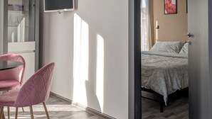 Une chambre moderne avec un lit, une télévision et un fauteuil rose.