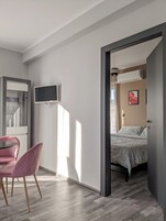 Una camera da letto moderna con un letto, una televisione e una poltrona rosa.