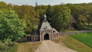 A small brick building with a dome and a statue on top, surrounded by trees and a stone wall. - Knuthenborg Safaripark (Bandholm)