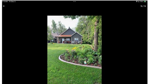 A house with a red roof, surrounded by a well-maintained lawn and a garden with various plants and flowers. - EAA 2026  3-bedroom lake house on lake poygan (Winneconne)