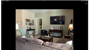 A living room with a beige sofa, a black chair, a coffee table, a fireplace, and a flat-screen TV mounted on the wall. - EAA 2026  3-bedroom lake house on lake poygan (Winneconne)