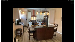 A kitchen with a central island, wooden chairs, and pendant lighting. - EAA 2026  3-bedroom lake house on lake poygan (Winneconne)