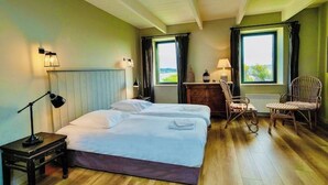 Ein Hotelzimmer mit zwei Betten, einem Schreibtisch, einem Stuhl und Blick ins Freie.