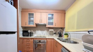 Eine kleine Küche mit Holzausstattung, Backofen, Geschirrspüler und Mikrowelle.
