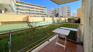 Ein Balkon mit Blick auf ein Sportfeld, einem Metallgeländer und einem weißen Tisch.