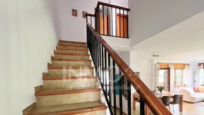 Eine Treppe mit hölzernen Stufen und schwarzen Geländern, die zu einer zweiten Etage führt.