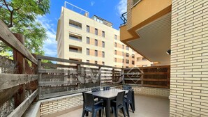 Ein Balkon mit Tisch und Stühlen, ein Holzzaun und ein Gebäude im Hintergrund.