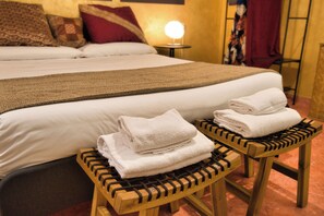 A neatly made bed with a white comforter and a brown throw blanket. There are two wooden stools with towels on them. - Pied à Terre De Charme. A magnificent terrace in the historic center of Verona. (Verona)