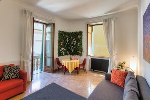 A living room with a sofa, a table with chairs, a decorative wall, and a window. - Pied à Terre De Charme. A magnificent terrace in the historic center of Verona. (Verona)