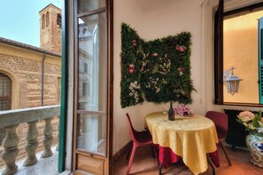 A balcony with a view of a historic building, a table with a gold tablecloth, red chairs, and a decorative wall with flowers. - Pied à Terre De Charme. A magnificent terrace in the historic center of Verona. (Verona)