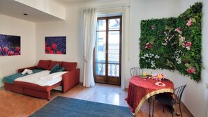 Et værelse med en rød sofa, et spisebord med et rødt skremsel og en grøn væg med blomsterdekoration.