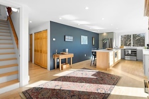 Eine moderne Küche mit Holzschränken, ein Essbereich mit Tisch und Stühlen sowie eine Treppe zu einem weiteren Raum.