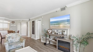 Una sala de estar con sofá, una mesa de centro, chimenea, televisor y planta.