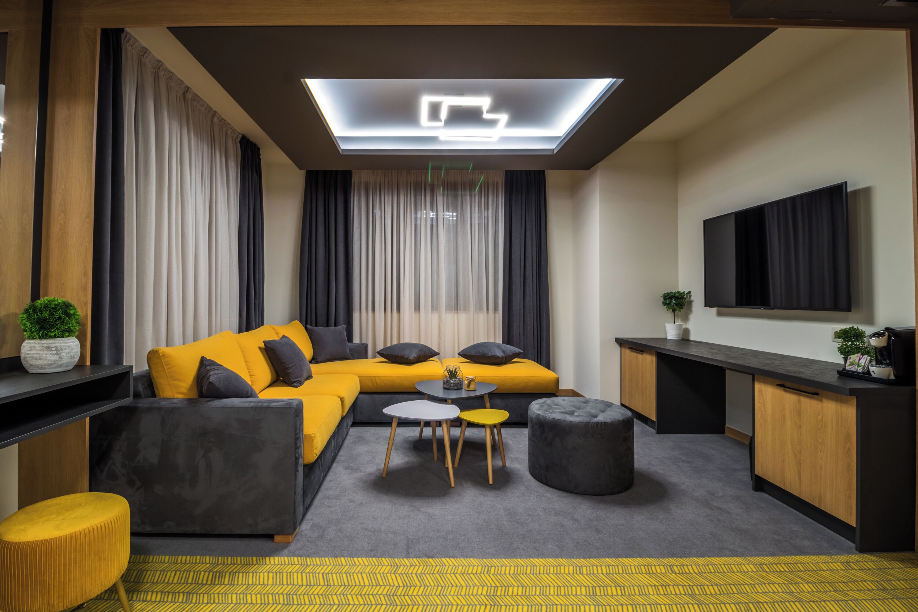Uma sala de estar moderna com sofá, banqueta, mesa de centro e televisão de tela plana.