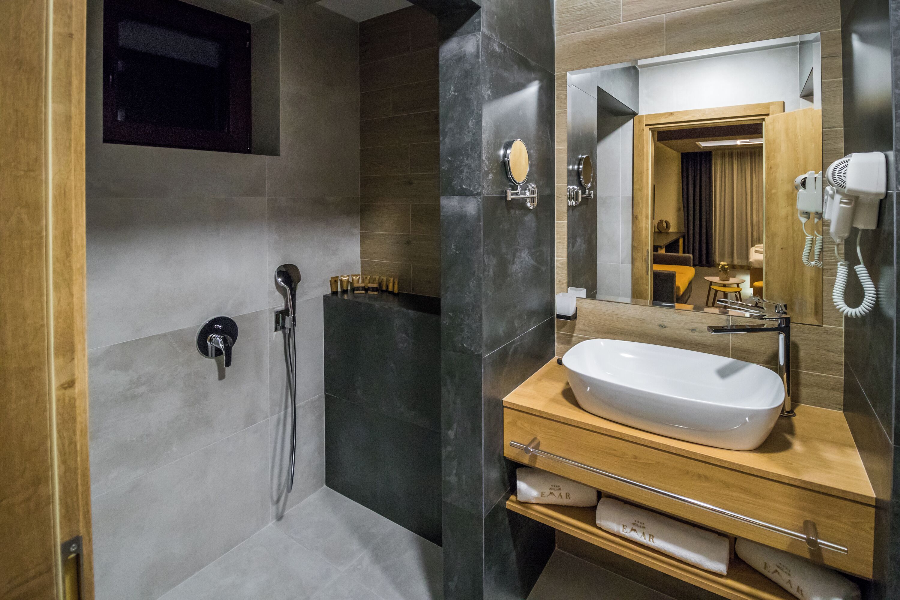 Une salle de bain moderne avec un grand miroir, un lavabo blanc et un espace douche.