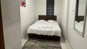 A small, neatly arranged bedroom with a single bed, a large mirror, and a ceiling light fixture. - Acar apart otel (Antalya)