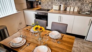 A dining table set with plates, cutlery, and wine glasses, with a vase of sunflowers in the center.