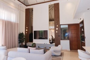 A modern living room with a sofa set, a flat-screen TV, and a wooden cabinet. - Bungallow 3BR With Pool and Patio in Cap Cana (Punta Cana)
