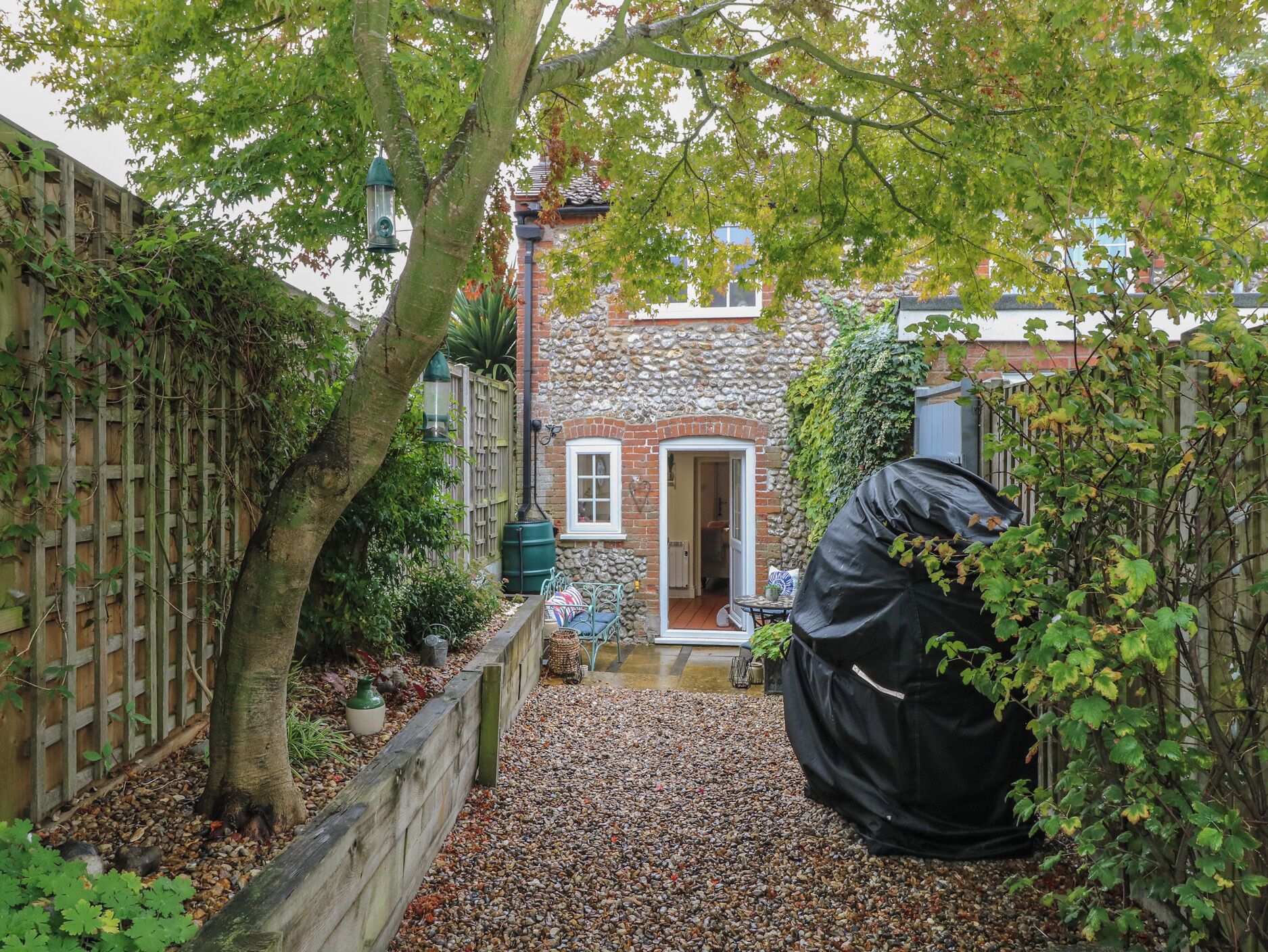 A stone house with a wooden fence, a gravel path, and a covered outdoor seating area.