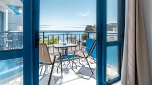 Uma varanda com mesa e cadeiras, vista para o mar e guarda-corpo azul.