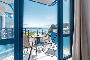 Ein Balkon mit Tisch und Stühlen, Blick aufs Meer und einem blauen Geländer.