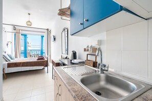Een moderne keuken met een gootsteen, kasten en uitzicht op het balkon.