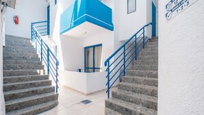 A staircase with blue railings leading to a landing with a door and a window.