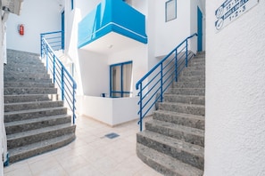 A staircase with blue railings leading to a landing with a door and a window. - Holiday Home 'Yamas Luxury House' with Sea View, Wi-Fi and Air Conditioning (Archangelos)