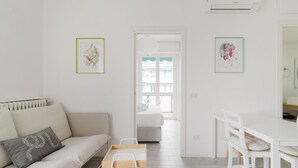Een moderne woonkamer met een bank, een eettafel en twee bloemrijke kunstwerken in lijsten aan de wanden.