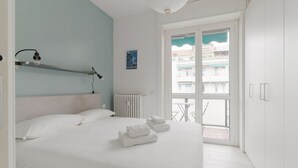 Een slaapkamer met een bed, een radiator, een raam met uitzicht en een handdoek op het bed.