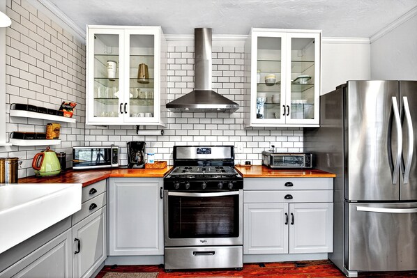 A modern kitchen with white cabinets, a stainless steel range, a microwave, and a refrigerator.