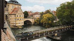 A historic town with a river, a bridge with flower boxes, and traditional half-timbered buildings. - HOY bamberg boutique hotel (Bamberg)
