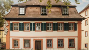 A two-story building with a traditional architectural style, featuring multiple windows with shutters, a prominent entrance, and a tiled roof. - HOY bamberg boutique hotel (Bamberg)