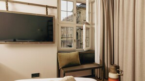 A hotel room with a bed, a bench by the window, a flat-screen TV, and a view of the outside. - HOY bamberg boutique hotel (Bamberg)