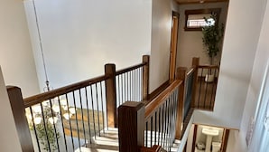 A wooden staircase with a railing, leading to an upper floor. - Luxury, Modern 4 Bedroom House with Full Basketball and Pickleball Courts! (Old Forge)