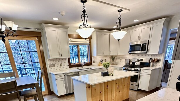 A modern kitchen with white cabinets, a wooden island, stainless steel appliances, and a large window. - Luxury, Modern 4 Bedroom House with Full Basketball and Pickleball Courts! (Old Forge)