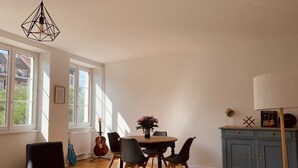 Een eetgedeelte met een ronde tafel, stoelen, een gitaar en een lamp.